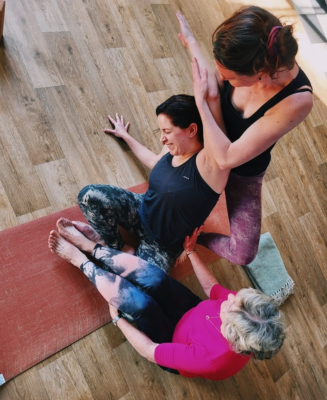 Yoga-docente en een andere vrouw helpen een vrouw in de juiste yoga-houding