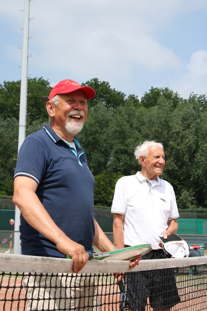 Twee lachende heren bij het tennisnet