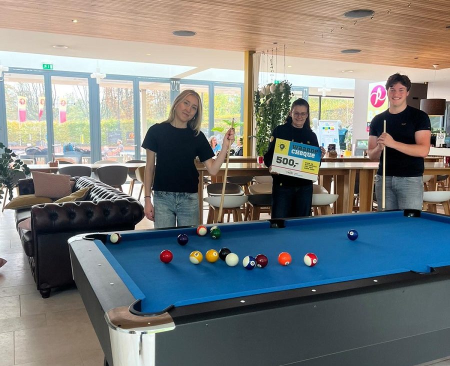 Een man en vrouw bij een biljarttafel; de middelste heeft een cheque van 500 euro in haar handen