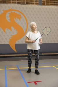 Alleskunner Monique (81) met een badmintonracket in haar ene en de shuttle in haar andere hand