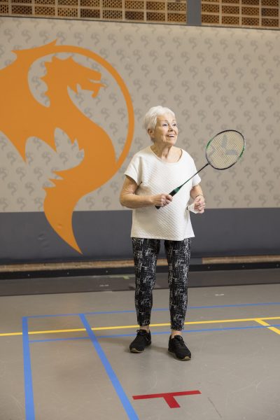 Alleskunner Monique (81) met een badmintonracket in haar ene en de shuttle in haar andere hand