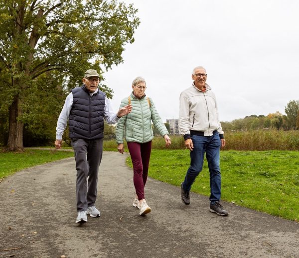 Twee mannen en een vrouw wandelen in de natuur