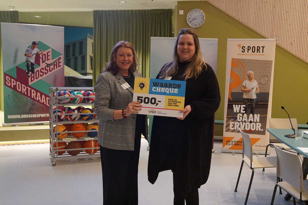 Twee vrouwen van BCH met een waardecheque van 500 euro in hun hand; op de achtergrond ´S-PORT-promotiemateriaal