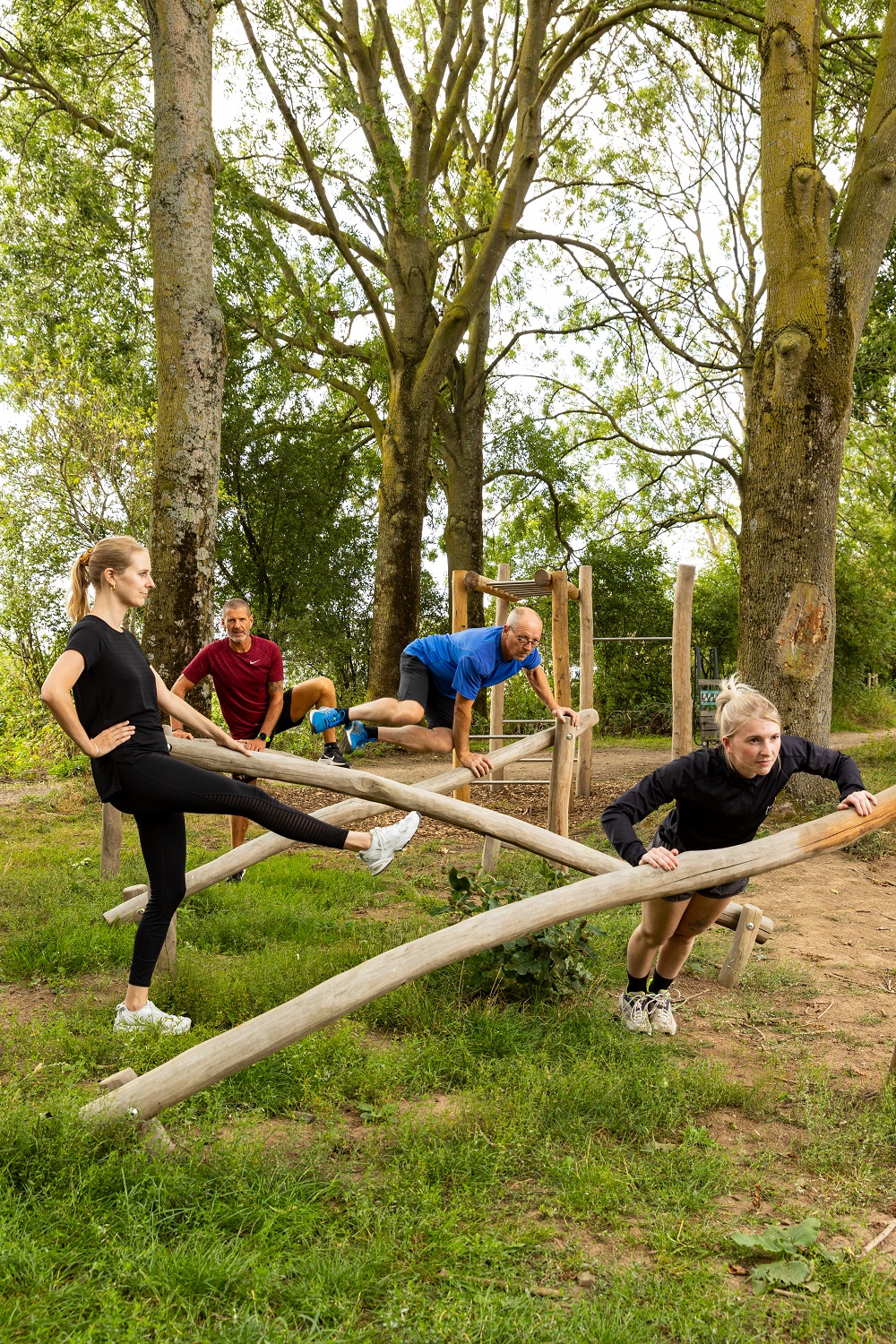 Mannen en vrouwen van verschillende leeftijden doen op toestellen oefeningen in bos
