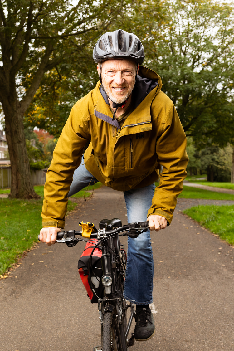 Corniel stapt energiek op zijn fiets in een groene omgeving