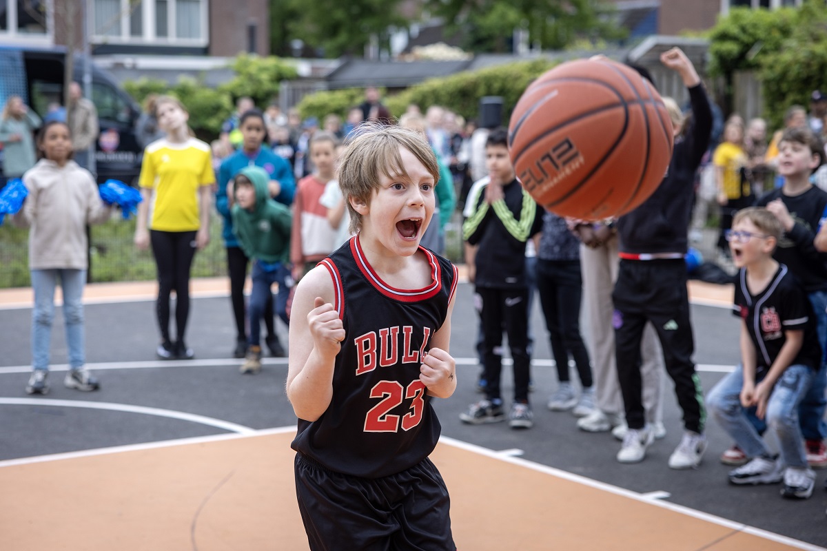 Enthousiste jongen met basketbal op 3X3 veldje Rompert; het publiek is al even enthousiast.