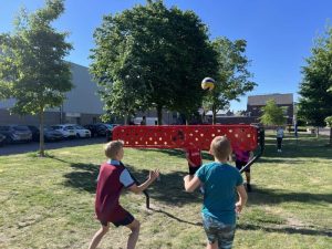Kinderen spelen de bal over, in het midden een rood net