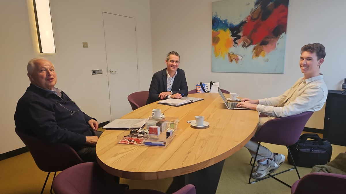 Drie mannen in gesprek in een kantoorruimte