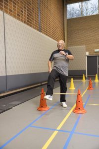 Roy (71) stapt lachend over hindernissen in sportzaal