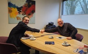 Twee lachende mannen schudden elkaar de hand