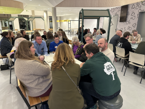 Groepen mensen aan verschillende tafels in gesprek met elkaar