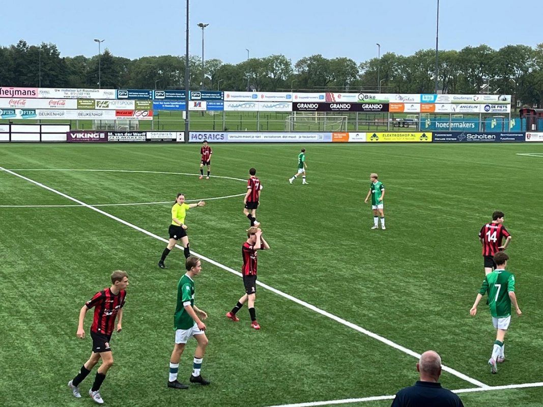 Fenne Vrehen steekt hand uit op voetbalveld met spelers om zich heen