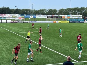 Fenne Vrehen steekt hand uit op voetbalveld met spelers om zich heen