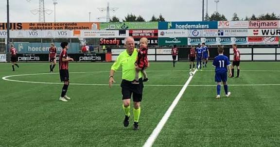 Lambert loopt met een klein kind op zijn arm het veld af