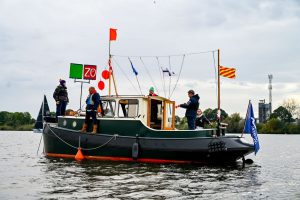 Vijf mensen op een boot met opvallende vlaggen