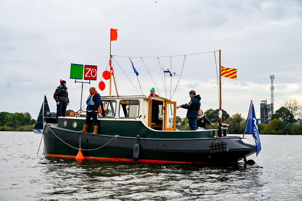 Vijf mensen op een boot met opvallende vlaggen