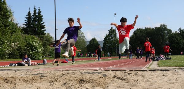 Twee jongens maken tegelijk een sprong en 'hangen' boven zandbak