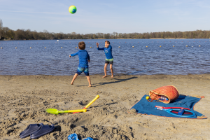 Jongens houden met strandbal hoog op stand aan zwemplas