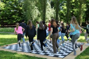 Jongeren dansen buiten in het groen op een zwart-wit-geblokte vloer
