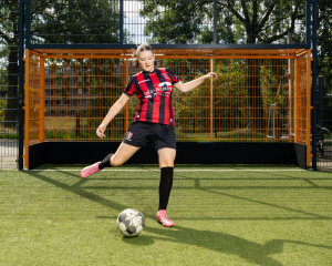 Een jonge vrouw in sportkleding in actie vlak voordat ze tegen een voetbal trapt
