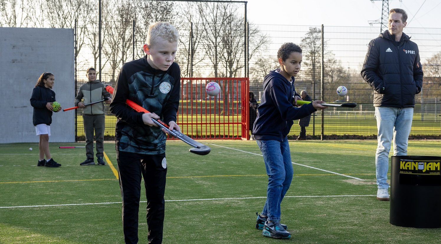 Twee jongens houden vol concentratie de bal hoog met hun hockeystick