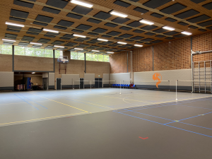 Overzichtsfoto van sportzaal met netten in het veld en een oranje draak op de muur in boarding