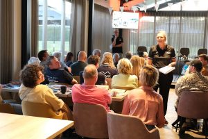 Vrouw met logo ´S-PORT loopt door een zaal van mensen